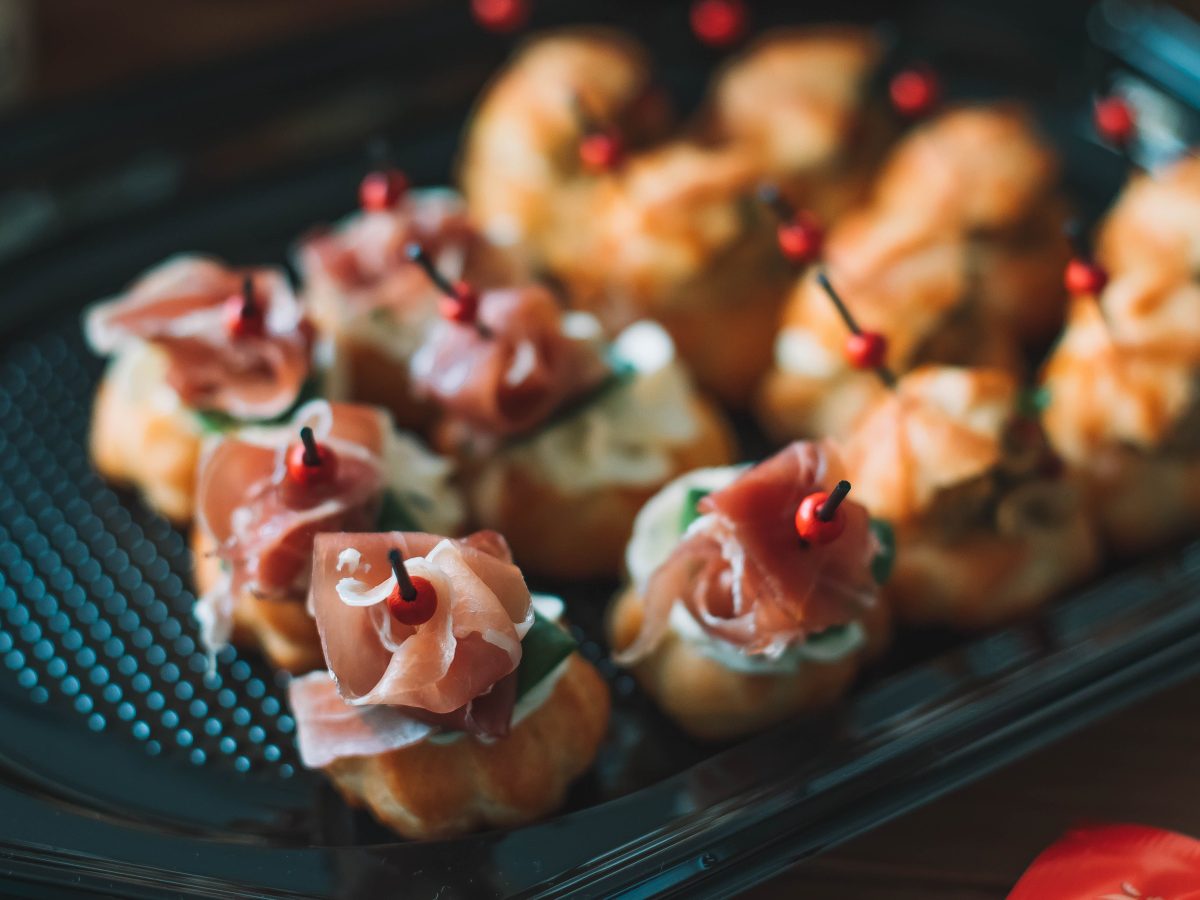 Choux salés garnis de jambon cru sur un plateau, présentés en pièces pour l'apéritif