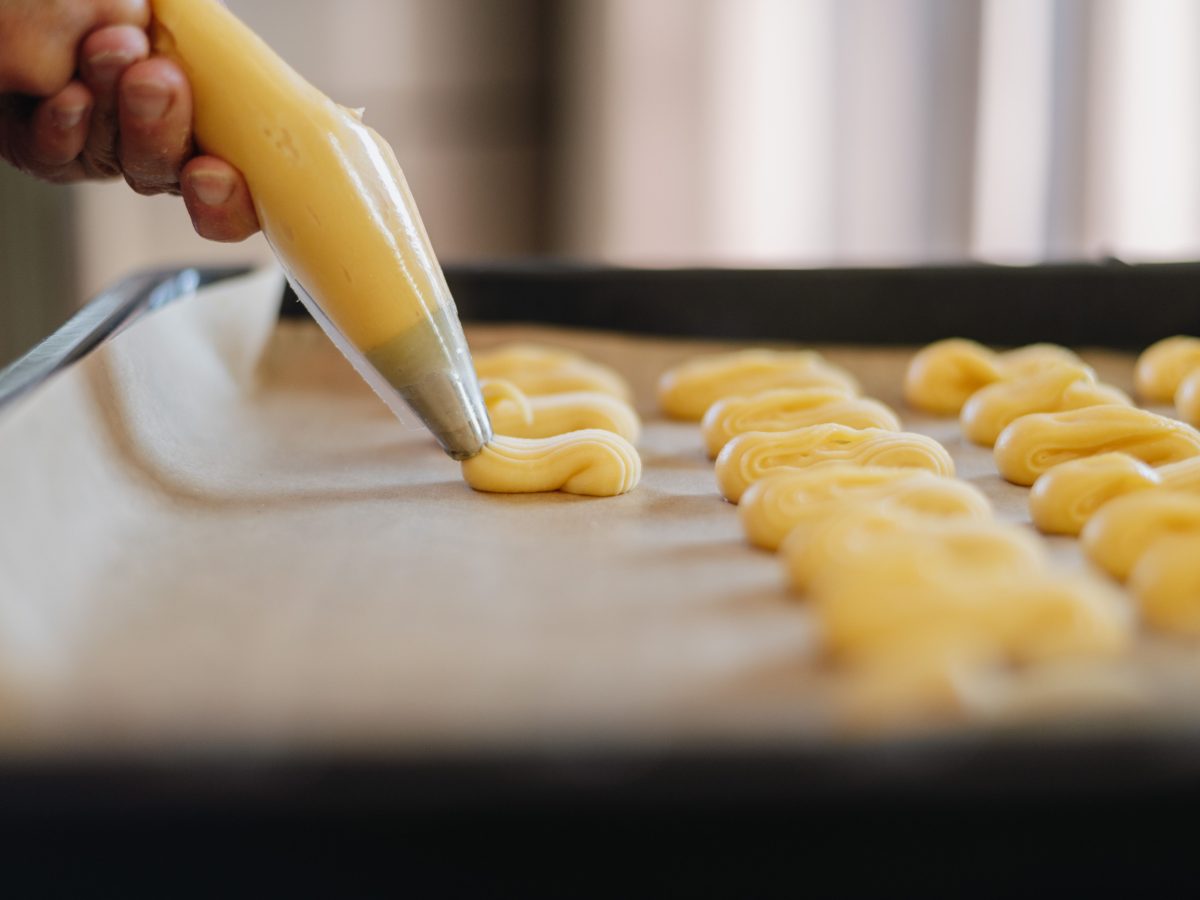 Pâte à choux pochée à la douille cannelée en bâtonnets sur plaque