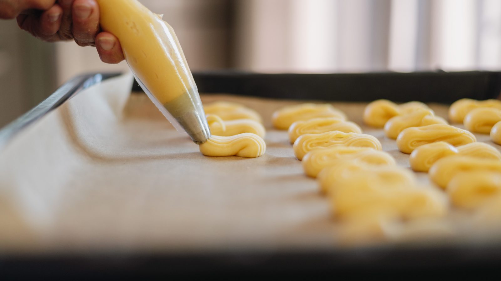 Pâte à choux pochée à la douille cannelée en bâtonnets sur plaque