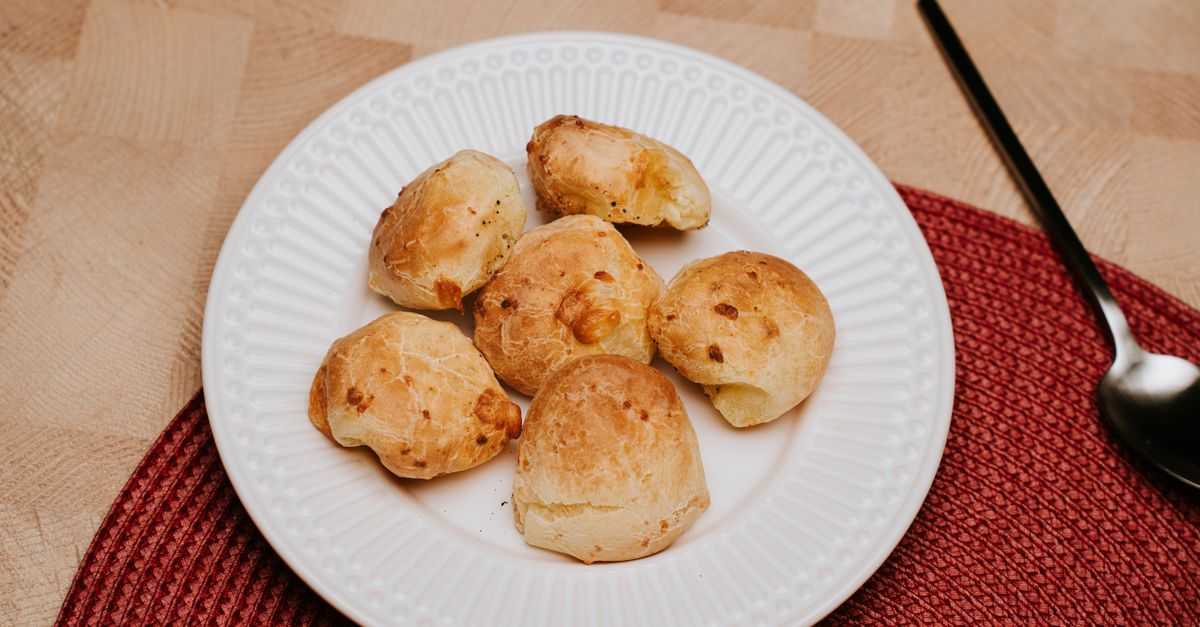 Gougères dorées présentées dans une assiette, fentes ouvertes sur le dessus avec de petites taches de fromage fondu visibles