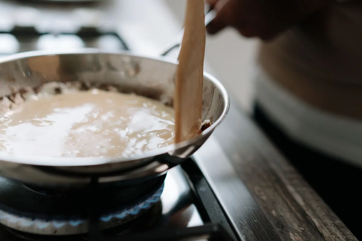 Panade de pâte à choux travaillée à la spatule en bois dans une casserole sur le feu