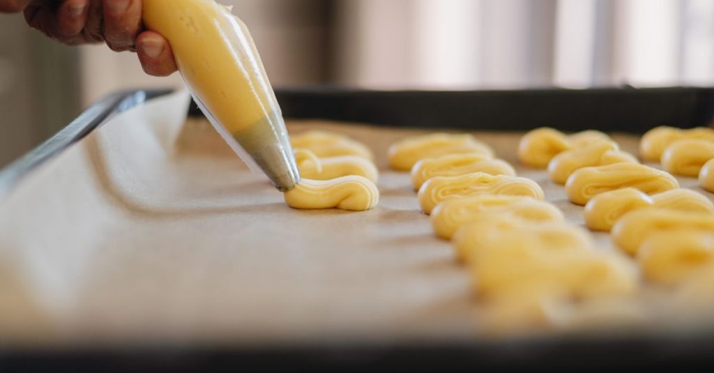 Pâte à choux dressée à la poche sur une plaque, avant cuisson