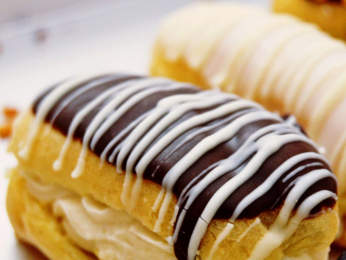 Eclair coupe montrant un glacage au fondant chocolat brillant, decore de filets de fondant blanc