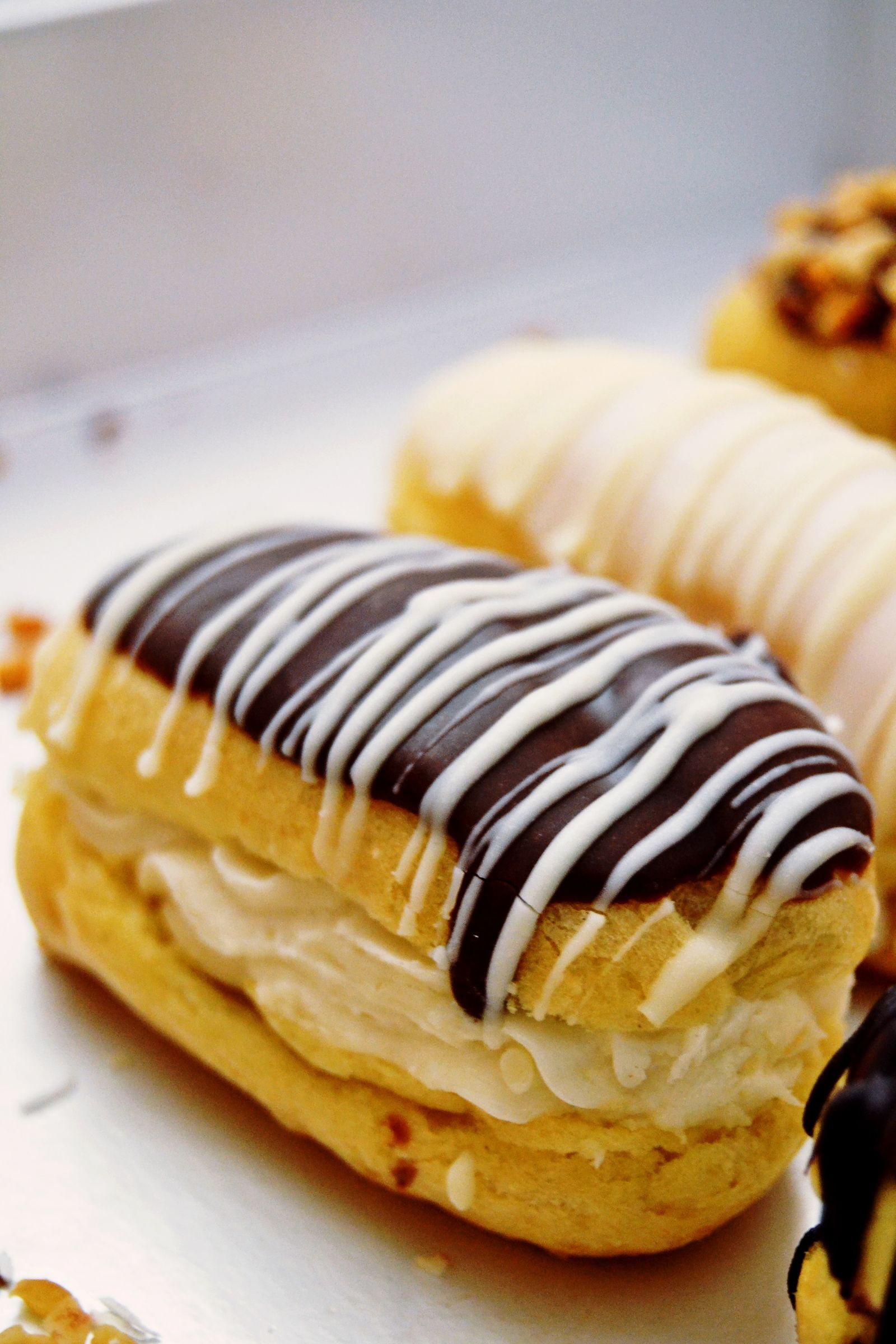 Eclair coupé montrant un glaçage au fondant chocolat brillant, décoré de filets de fondant blanc