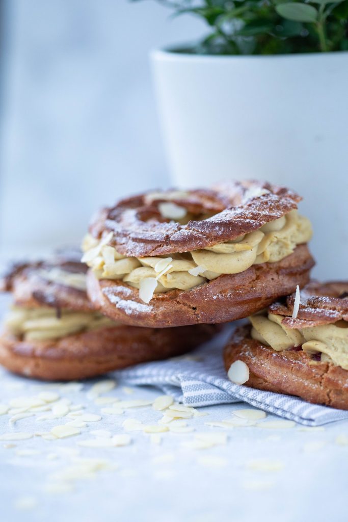 Paris-Brest individuels garnis de crème pralinée, parsemés d'amandes effilées et de sucre glace
